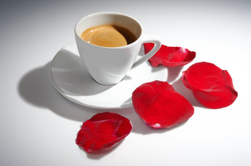 Cup of coffee and rose petals on white background by sidelight