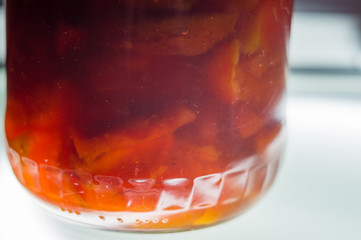 Bright translucent jam of different fruits in a glass jar