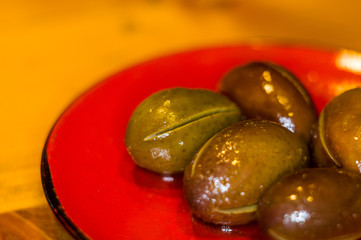 large marinated olives on a red saucer