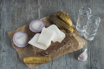 Pickled cucumbers , bread and salo on dark wooden table. Traditional Russian snack.