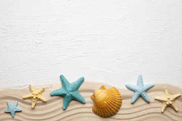 Fototapeta na wymiar Summertime background - seashells, beach sand and white plastered background