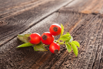 Fresh rose hips on wooden background.