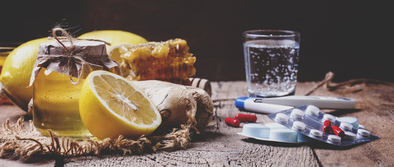Choose between drugs for colds and flu: traditional tablets and alternative natural remedies. Vintage wooden background, selective focus and toned image