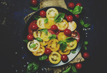 Salad from colorful tomatoes, green basil, low key, top view and toned image