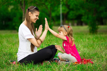 Fototapeta premium Mother and little daughter playing together in park. Outdoor Portrait of happy family. Happy Mother's Day Joy. Mom and Baby