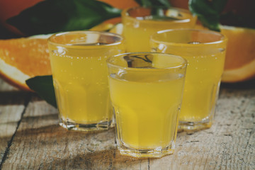 Orange soda on a background of fresh oranges on old wooden table, selective focus and toned image