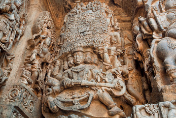 Magic gods and other sculptures on carved wall of 12th century historical Hoysaleswara Hindu temple, Halebidu, India.