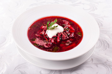 White bowl of traditional Ukranian soup borsch or vegetable beetroot soup with sour cream.