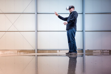 Construction worker standing at indoor construction site wearing vr eyeglasses or goggles, bright environment with space for your copytext or imagery projection