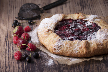 Galette with berries raspberries, strawberries and black currants with sugar powder