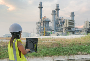 Engineering women are checking oil refineries and gas stations on notebooks. In the industrial area.