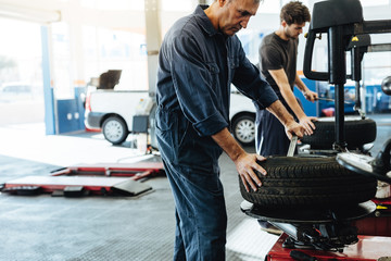 Mechanics working on tire replacing machines in service station