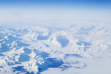 Fototapeta na wymiar Blue and white winter snow landscape from plane above over iceland traveling from Keflavik to canada