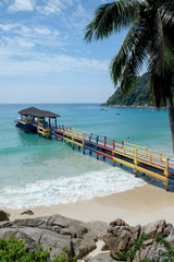 colorful jetty on a white sandy tropical beach and blue sea.