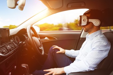 Naklejka premium man behind the wheel wearing a virtual reality helmet
