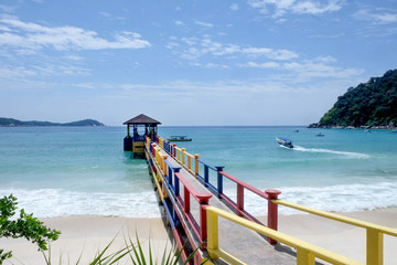 colorful jetty on a white sandy tropical beach and blue sea.