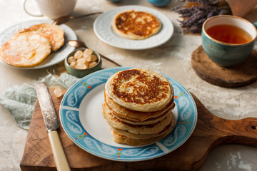 Tea, homemade pancakes, honey, cream sauce and lavender on light concrete table, romantic breakfast pancake party, various morning food, healthy lifestyle. Selective focus