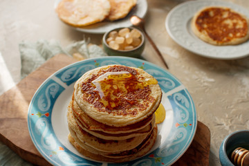Homemade pancakes and honey on light concrete table, romantic breakfast pancake party, various morning food, healthy lifestyle. Selective focus