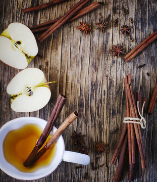Hot drink (apple tea, sider, punch) with cinnamon stick, star anise and clove. Seasonal mulled drink on wooden background. Hot drink with apples for autumn or winter time.