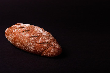 Tasty black bun with flour on black background. Text place