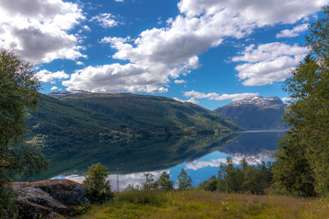 Norwegian mountain lake summer landscape. Clouds reflecting in the crystal clear water surface.
