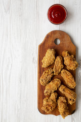 Chicken wings on a wooden board with red pepper sauce on white wooden table, top view. Space for text.