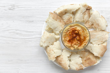 Hummus in bowl with roasted chickpeas, paprika, olive oil and pita bread, closeup. From above, top view. Copy space.