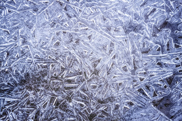 Beautiful frost ice crystals on frozen puddle water, blue color, background, closeup.