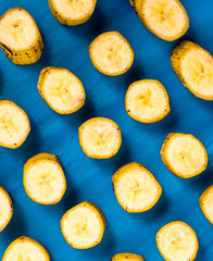 Sliced banana pattern on blue background, wooden table.