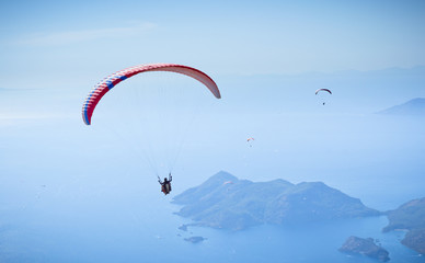 Parachute skydiver flying in clouds at top of mountains