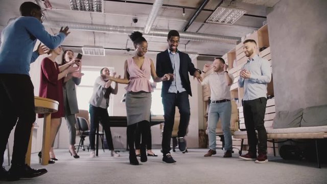 Multiethnic business people celebrate business achievement at casual office dance party in modern coworking slow motion.