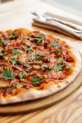 Pizza with meat, BBQ sauce, pickled cucumbers and parsley