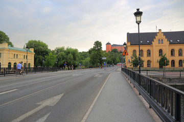 View on one of central streets in Uppsala, Sweden, Europe. Small bridge over river , yellow buildings, red castle far away. Beautiful backgrounds.
