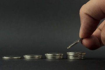 copy spaсe,  hand puts coins, one on one, in a row in ascending order