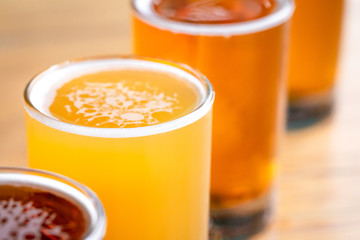 Macro close up on the foamy surface of an unfiltered ale, in a diagonal row of beer glasses