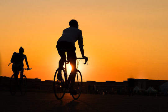  man and woman riding bicycle with sunset sky background