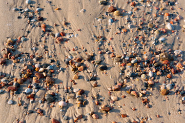Wet sea sand and small stones. Sea stones on the sand.