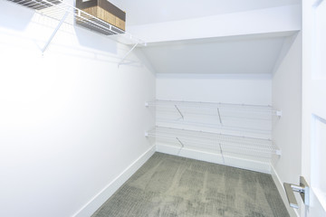 Empty walk-in closet with white walls and shelves.