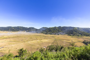 Fototapeta na wymiar Smoke rising from the Spider Rice fields during harvest season in Flores, Indonesia.