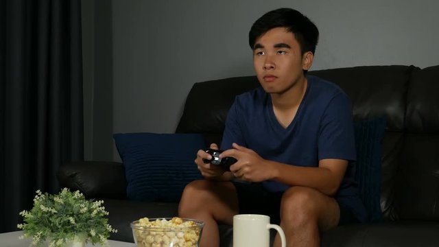 4k of young man playing video games on sofa at night