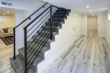 Empty white hallway with grey hardwood floor and a staircase.