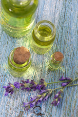 bottles of lavender,oil with fresh oregano leaves wooden Board on a blue background, top view