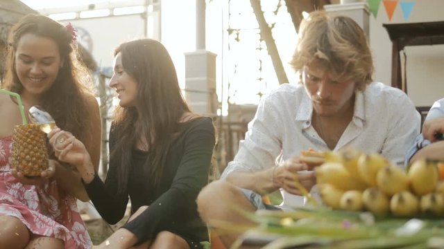 Happy group of people having fun, smiling, enjoying picnic party with drinks and food outdoors together. Young friends celebrating birthday. Holiday celebration festive party. Teenage lifestyle.