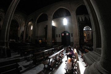 Obraz premium young man sitting alone inside a church in the light of a ray of sunlight coming through the window
