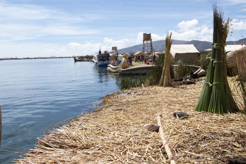 Landscape of the Uros floating islands in the magic blue colors of the Titicaca Lake with the Andes mountain range in the background.