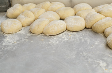 Fototapeta na wymiar Harvesting rolls on a floured baking sheet.