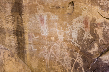 Cluster of ancient rock wall carvings depicting people and animals
