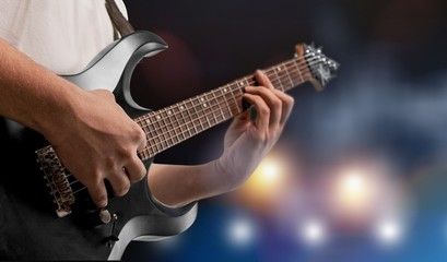 Male Guitarist playing music on dark background