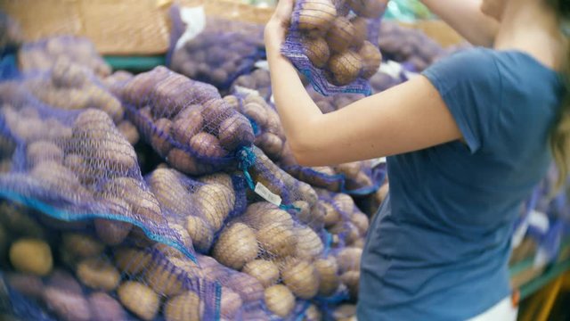 A woman in a supermarket buying vegetables, potatoes