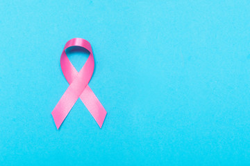 Pink ribbon awareness about breast cancer symbolic bow. isolated on blue background.